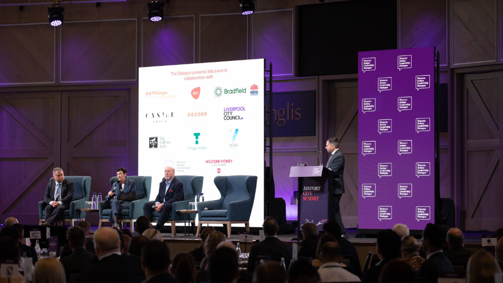 Four person panel in front of two LED screens