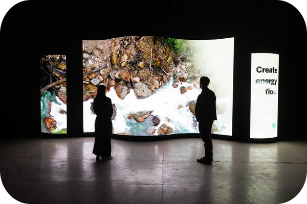 People standing in front of a curved LED screen
